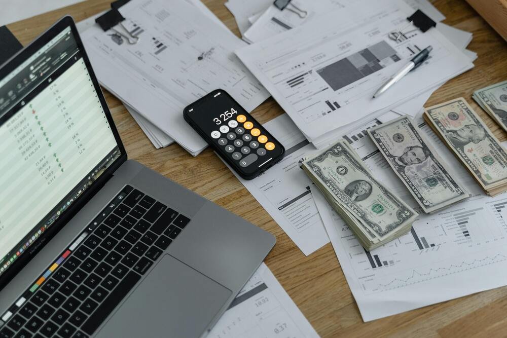 uma-mesa-com-notebook-e-algumas-notas-de-dolar
